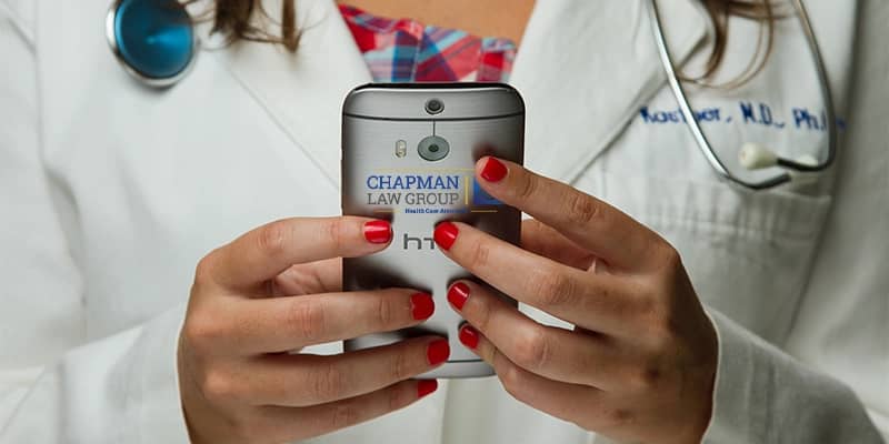 Doctor holding a smart phone looking up the Michigan anti-kickback statutes on the Chapman Law Group Website.