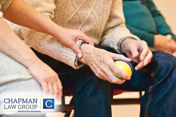 An aging patient in a regulated facility holding a ball.