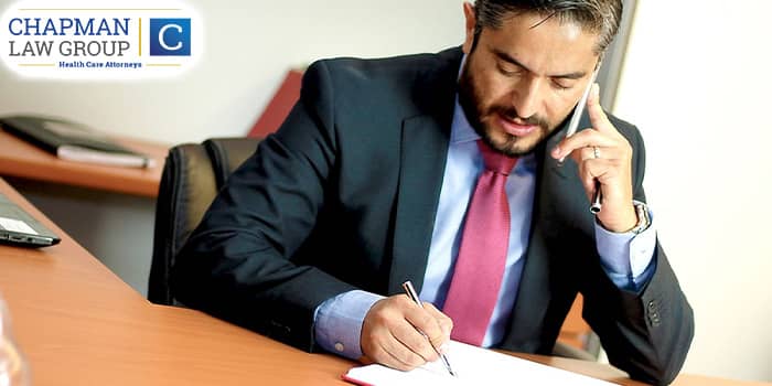Image of an attorney on the phone and writing on a notepad.