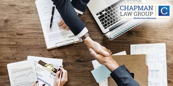 Healthcare providers shaking hands with a Chapman Law Group healthcare defense attorney.